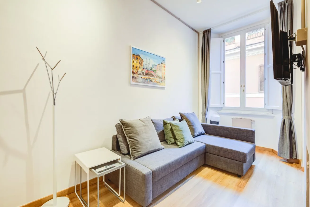 A bright living room with a gray sectional sofa beside a large window.