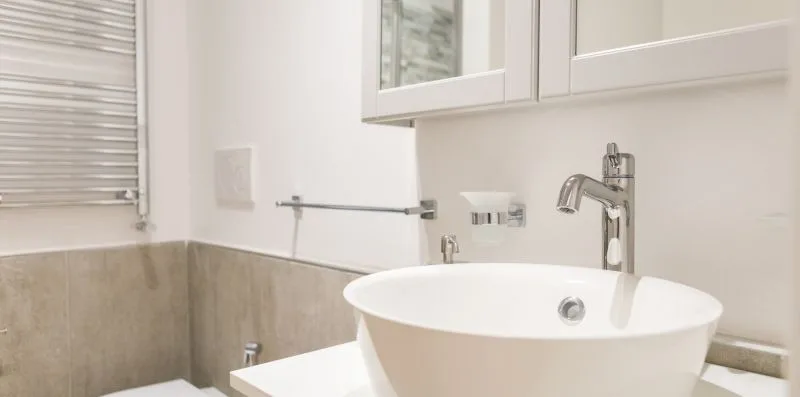 A bathroom vanity with a white vessel sink and wall-mounted fixtures.
