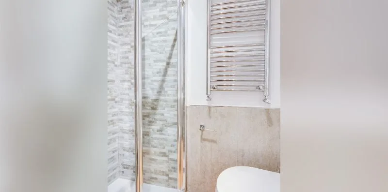 A bathroom with a glass shower and a window above the sink area.