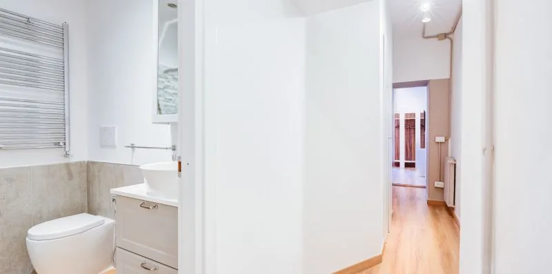 A bright bathroom with a toilet and sink beside an open doorway.