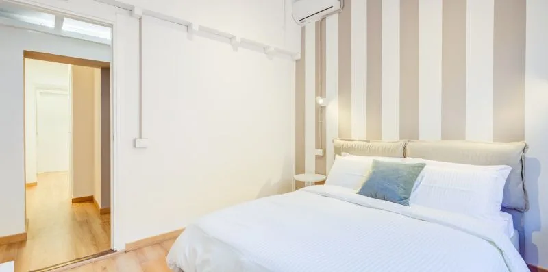 A bedroom with a bed, striped wall, and open doorway.