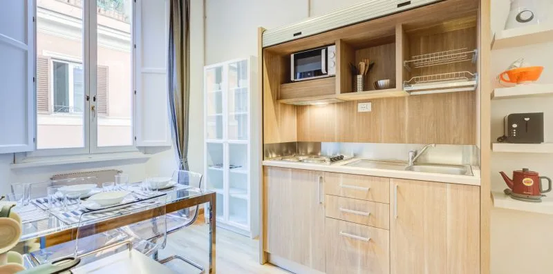 A bright kitchen with a wood-toned counter and a dining table by the windows.