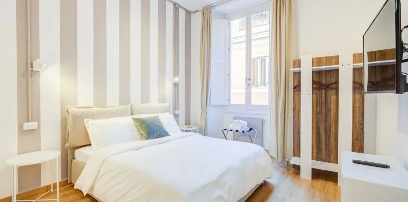 Un dormitorio luminoso con una cama junto a una ventana alta.