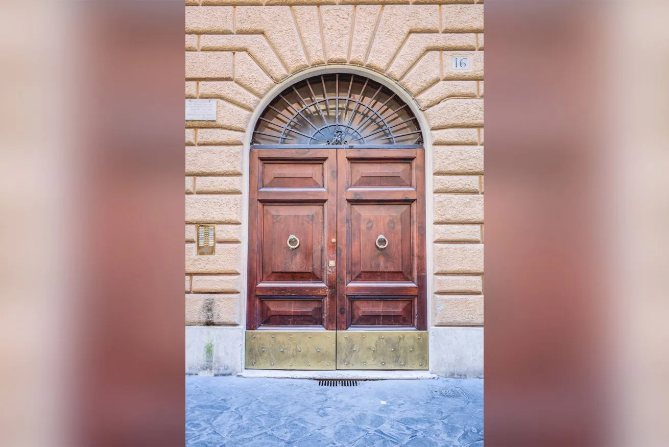 An arched wooden entrance door set into a stone facade.
