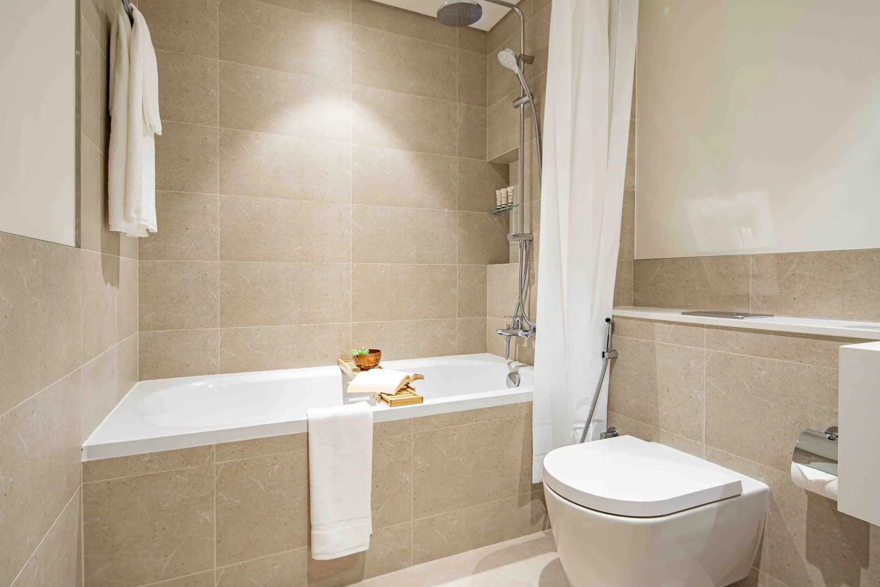 Un baño alicatado con bañera, ducha e inodoro.