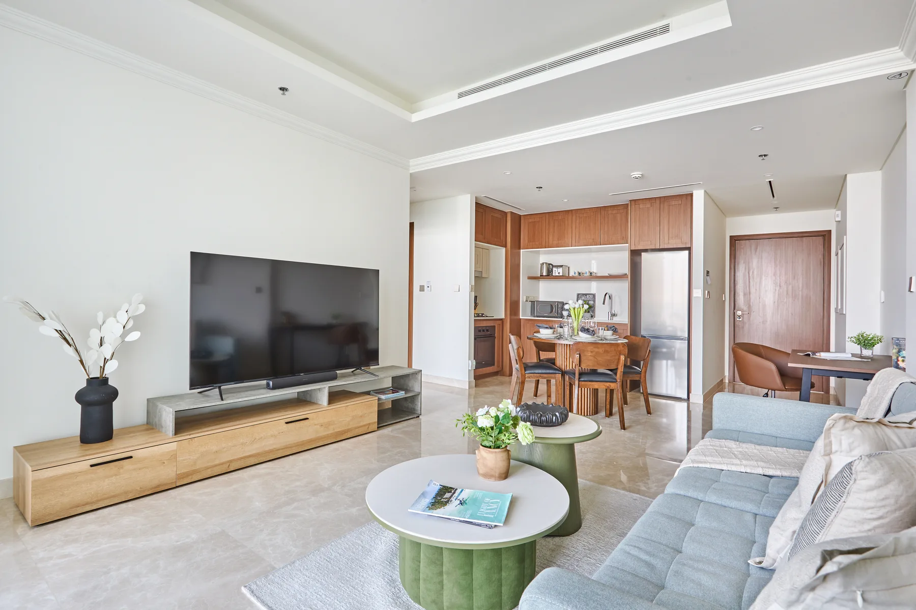 Una luminosa sala de estar y comedor con televisor, asientos y una mesa de comedor.