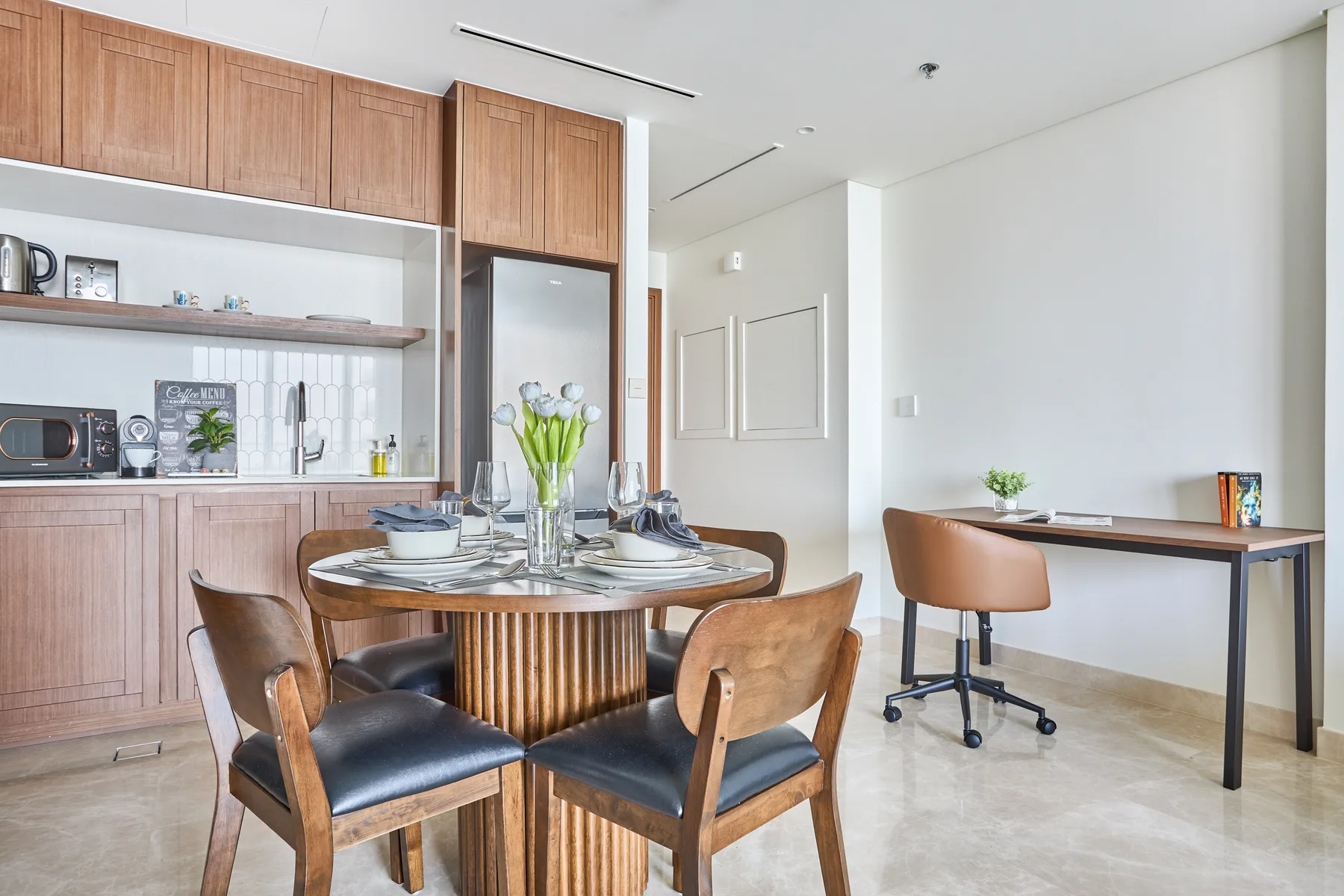 Un comedor con una mesa redonda y sillas junto a una cocina compacta.