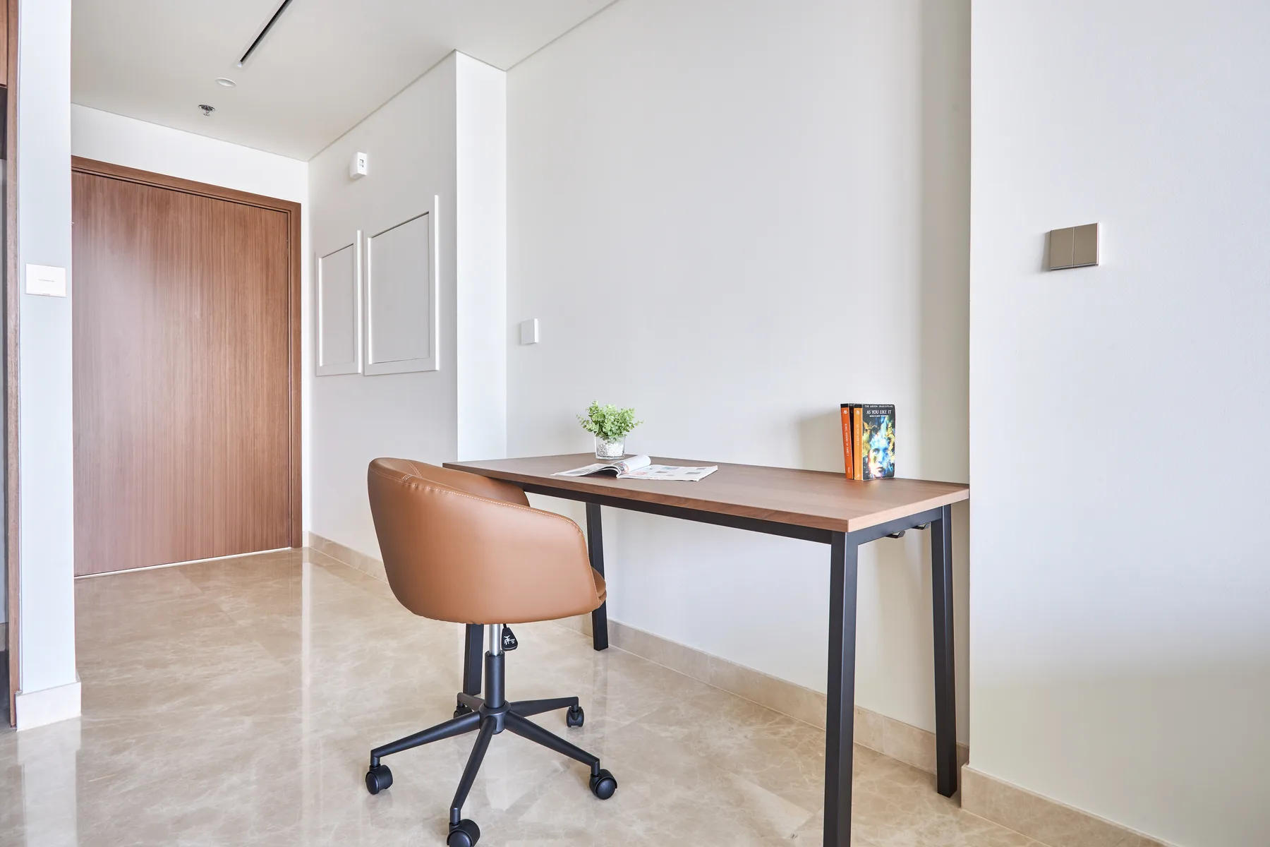 Una habitación luminosa con un escritorio y una silla giratoria marrón cerca de la entrada.