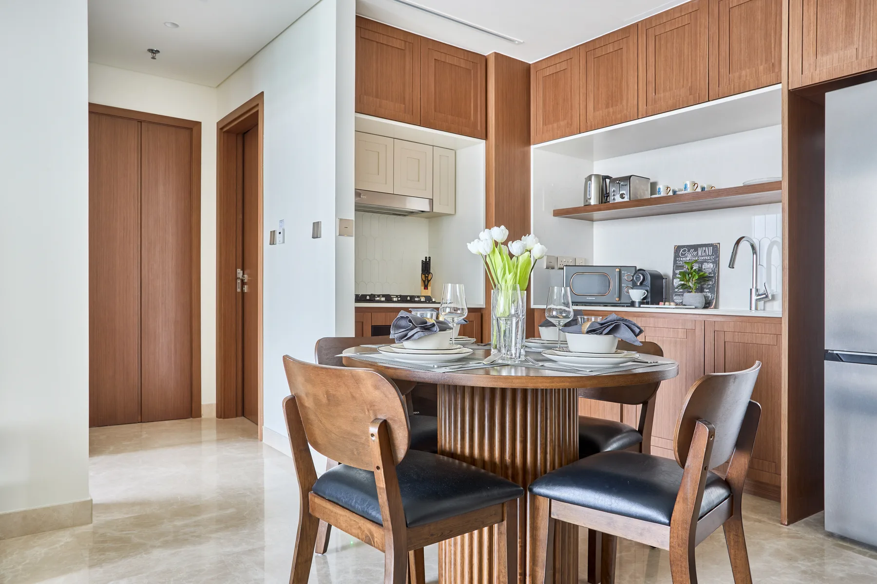 Comedor con una mesa redonda y asientos de madera junto a la cocina.