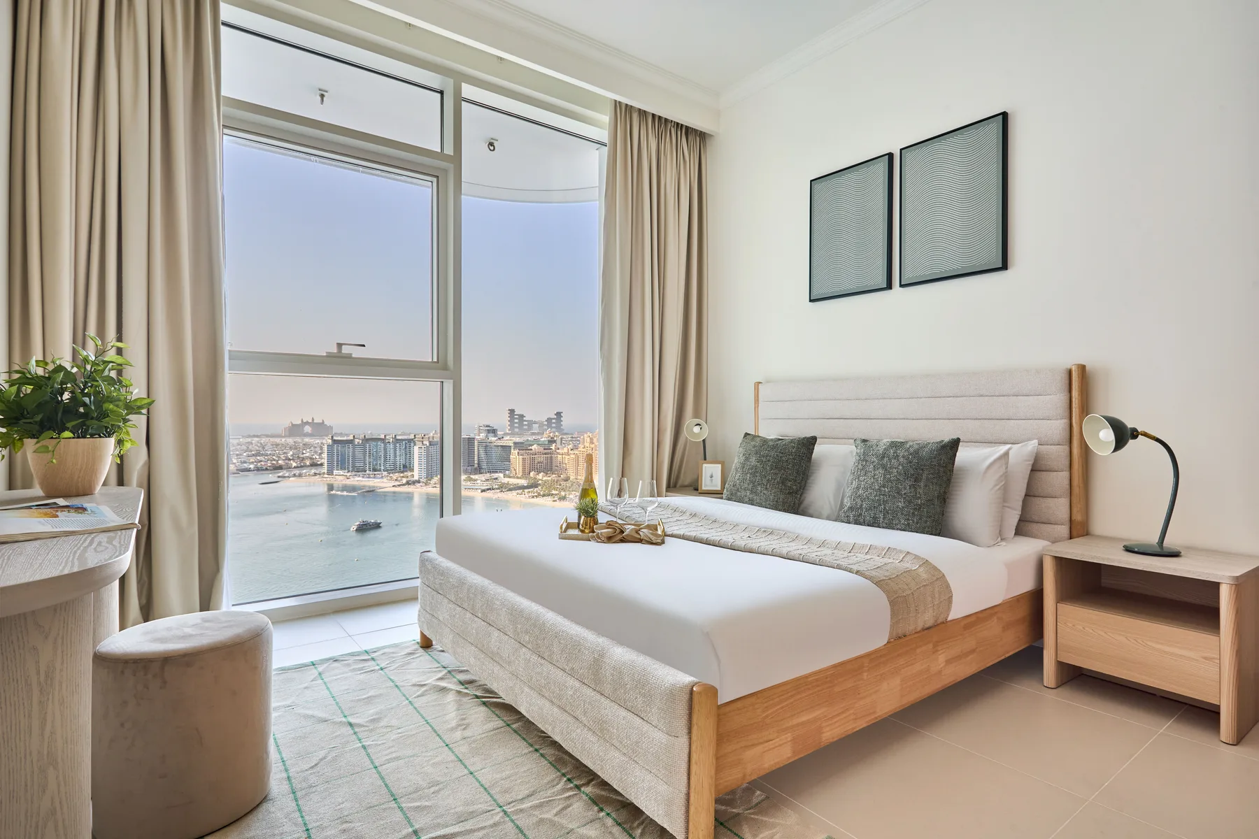 Un dormitorio luminoso con una cama bien tendida junto a grandes ventanas con vistas al agua.