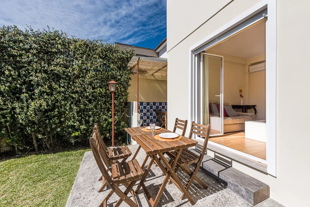 A patio dining area with a wooden table beside an open sliding glass door.