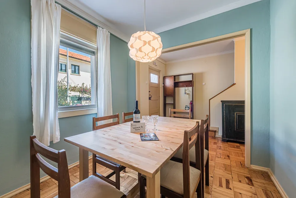 Comedor con una mesa de madera bajo una lámpara colgante.