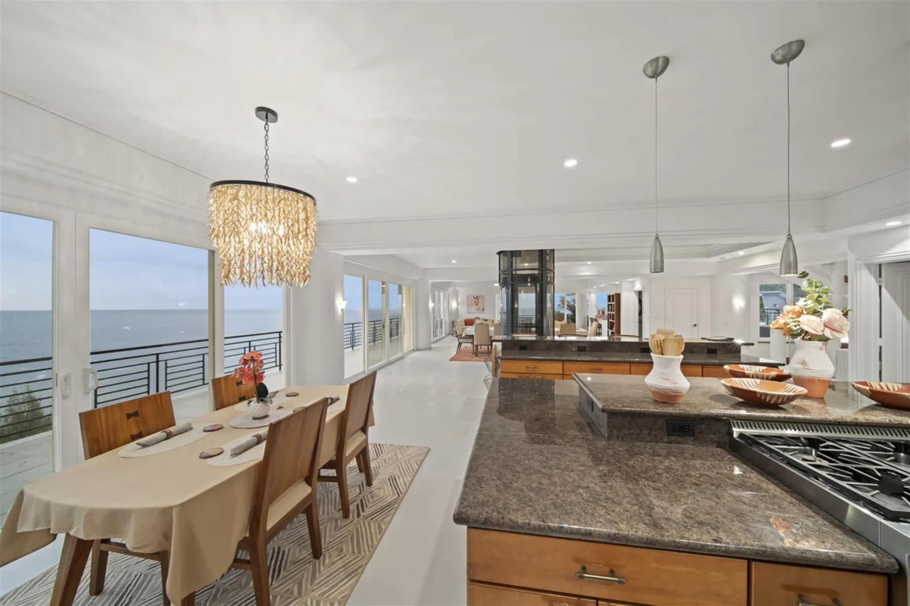 An open-plan dining and kitchen area overlooks the water through large windows.