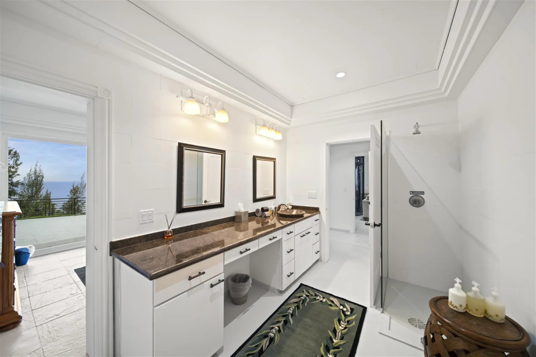 A bright bathroom with a long vanity and a glass shower.