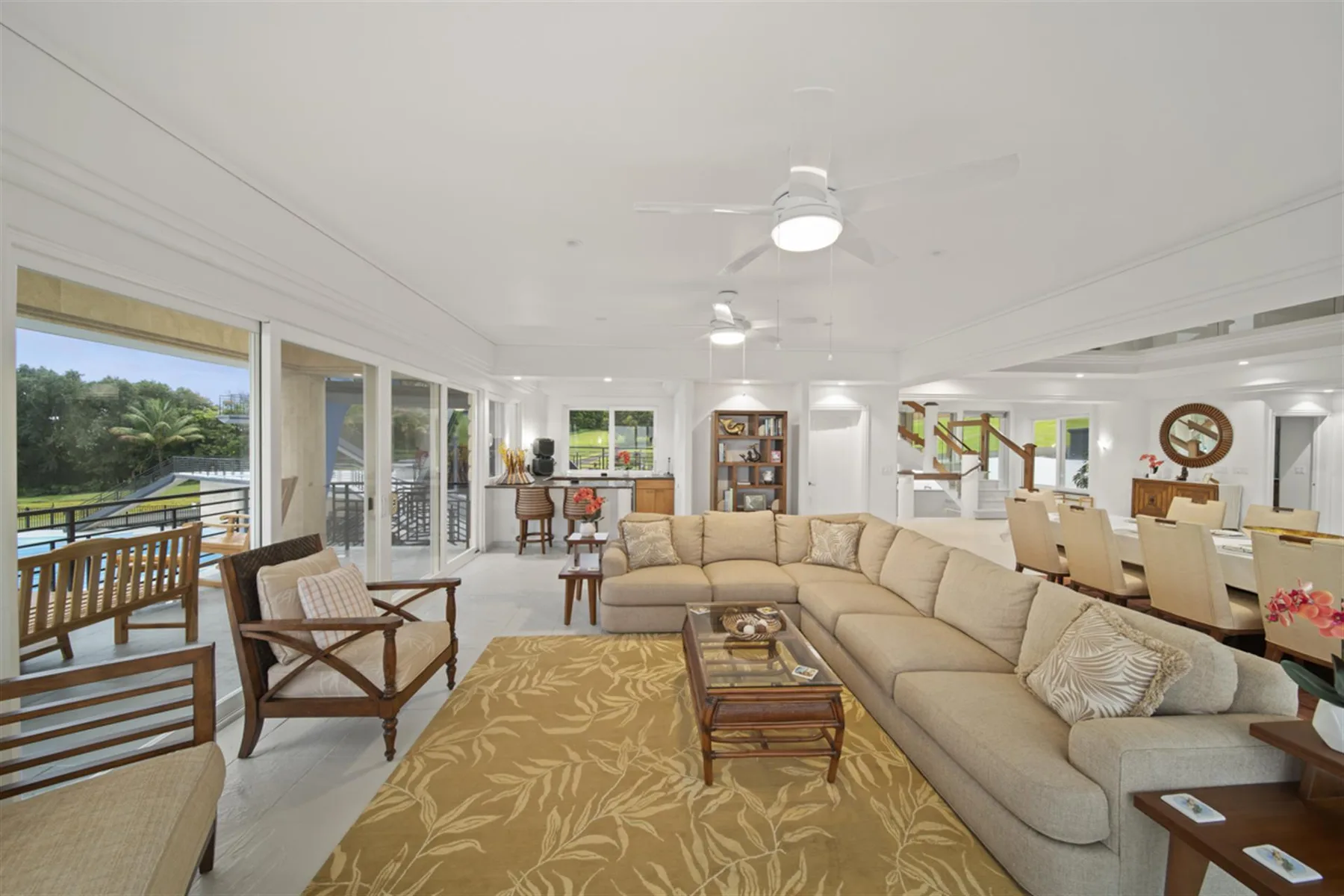 A bright living room with spacious seating and large windows overlooking greenery.
