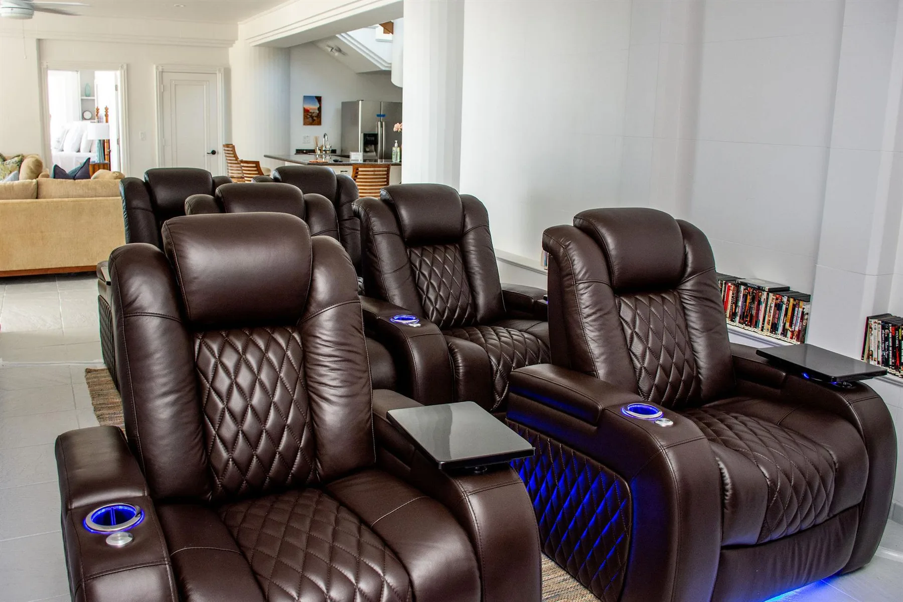 A living room with rows of dark leather seating and blue accent lighting.