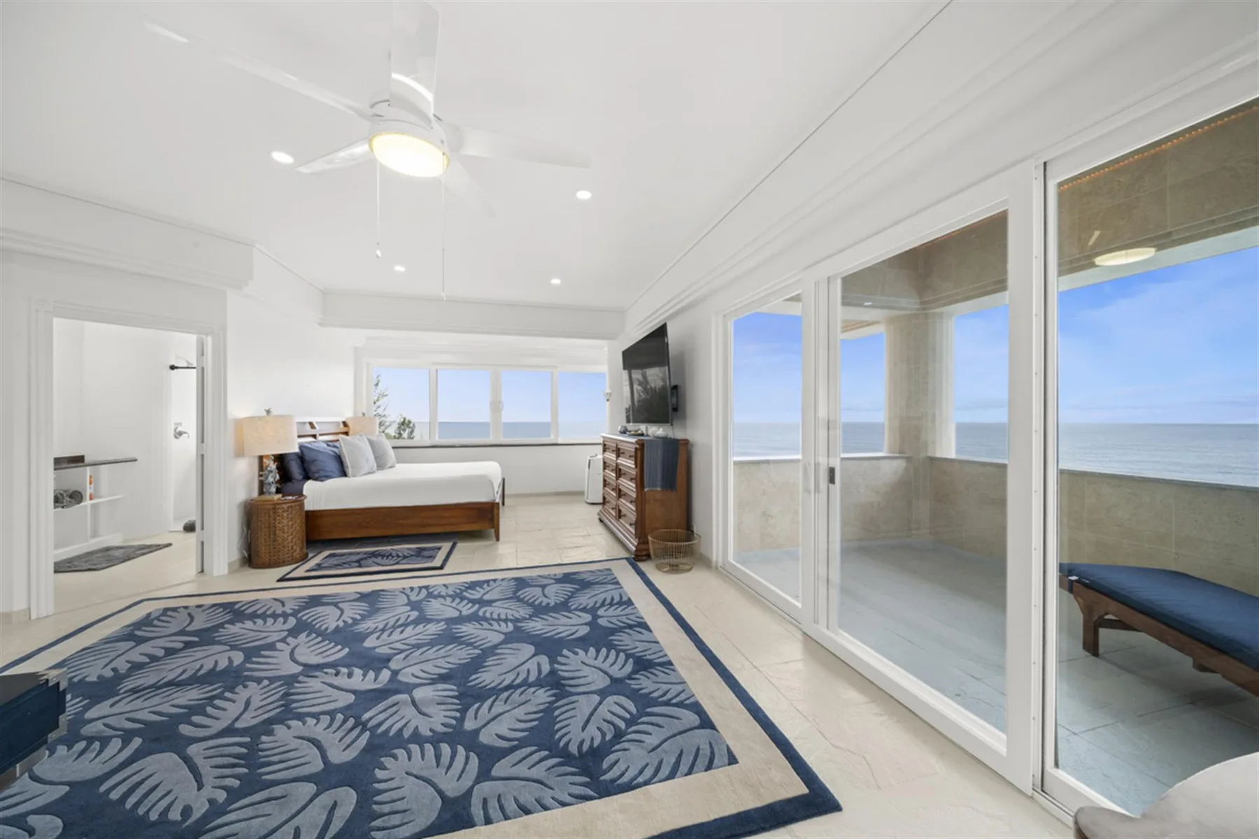A bright bedroom opens onto a balcony with ocean views.