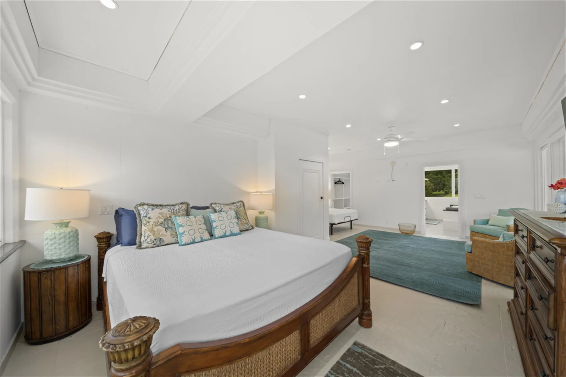 A bright bedroom with a large bed, bedside tables, and a rug.