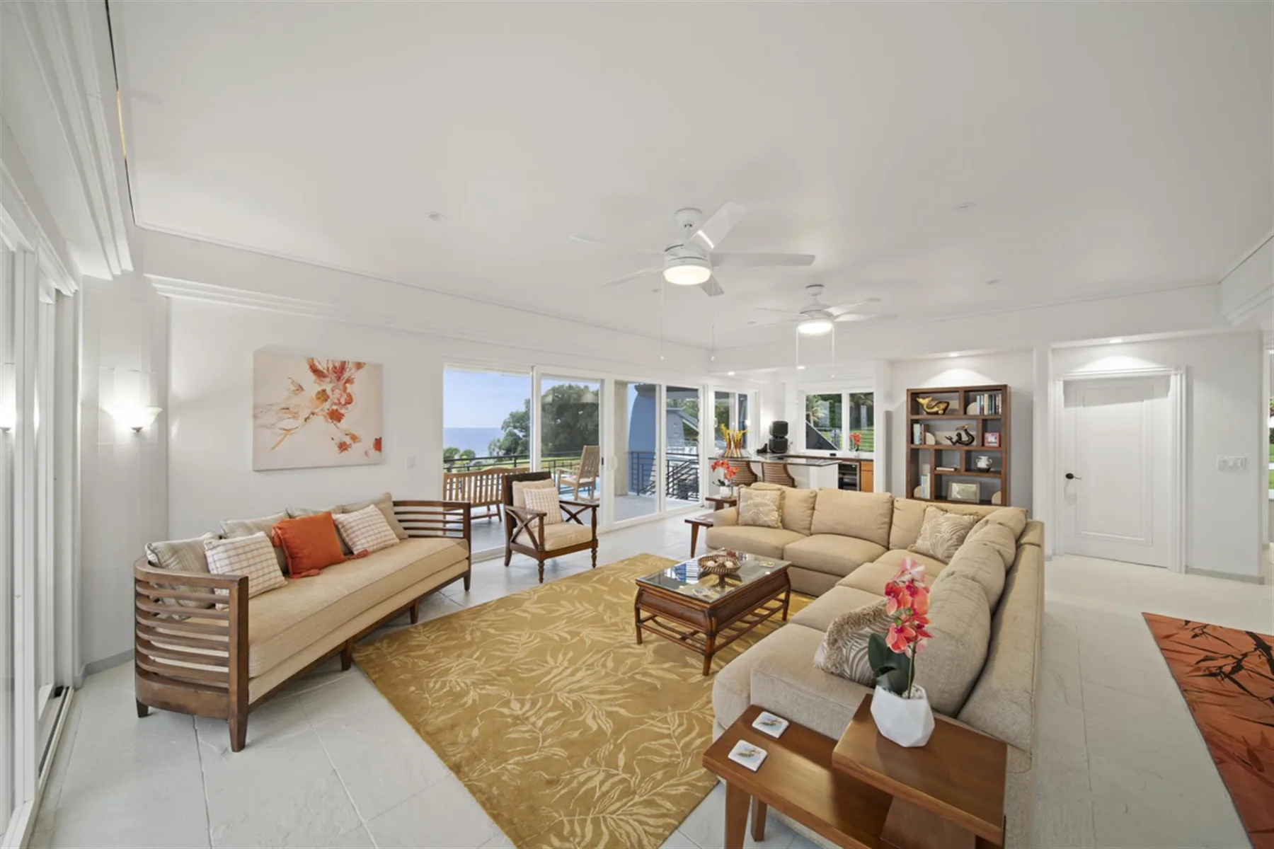 A bright living room with seating, a coffee table, and windows opening onto a patio.