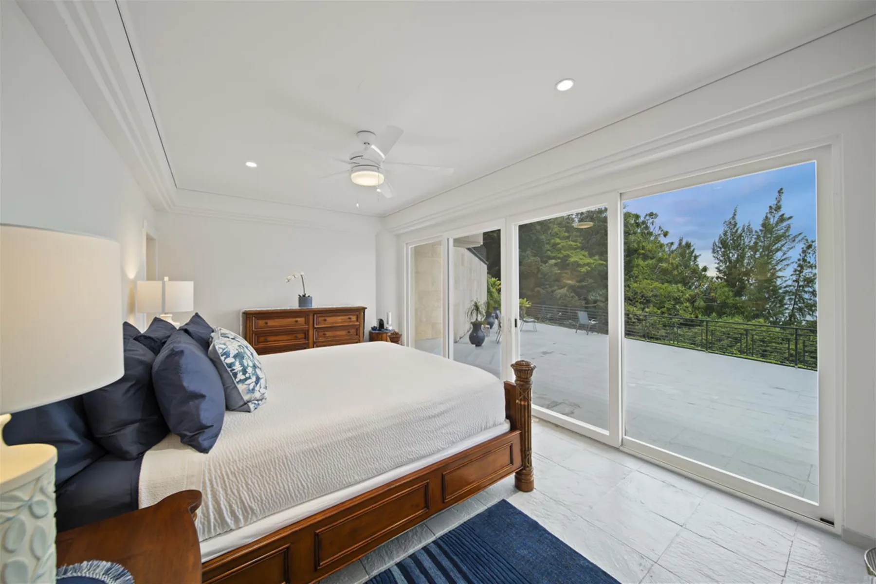 A bright bedroom with a large bed beside sliding glass doors opening onto a terrace.