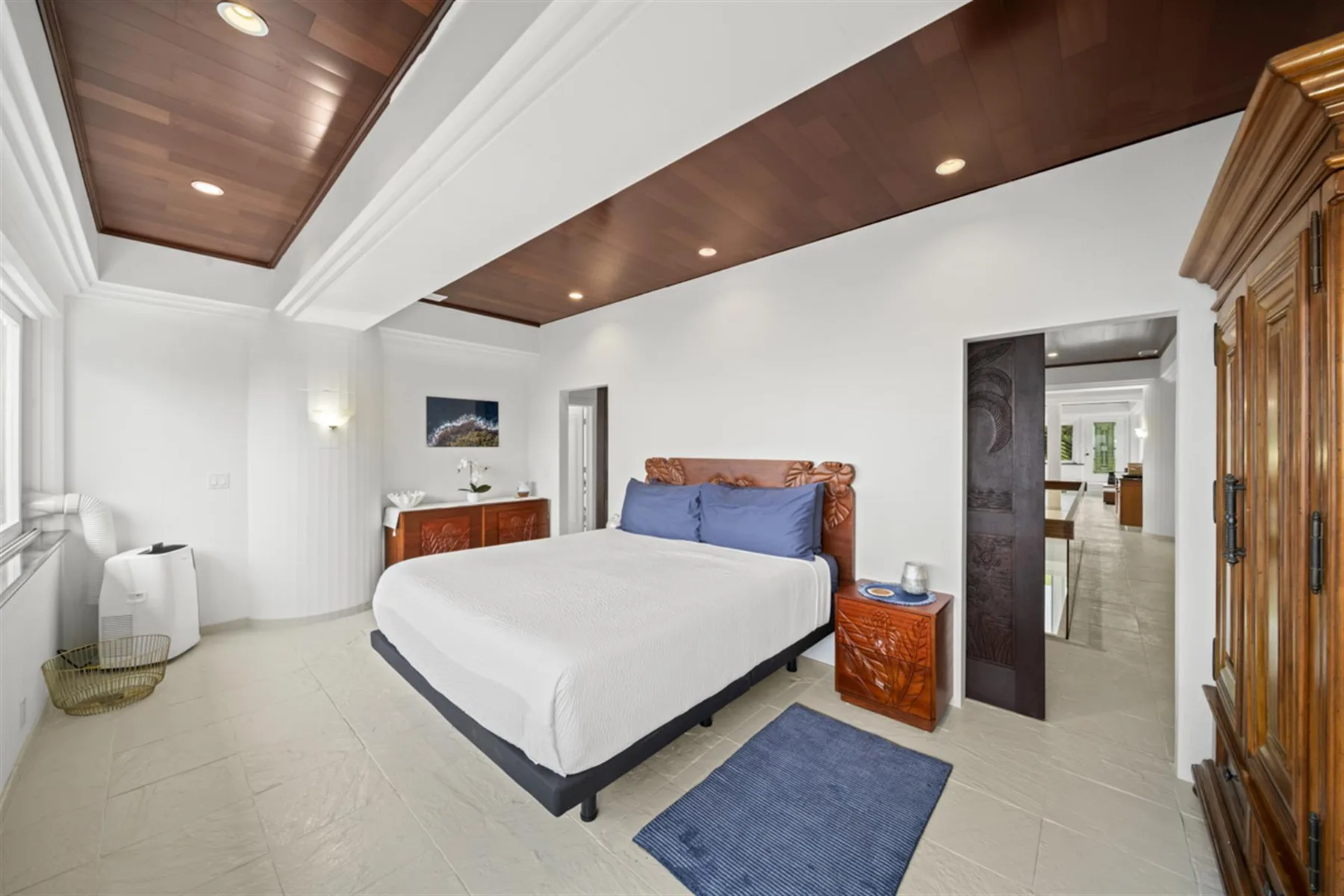 A bedroom with a neatly made bed and a wooden cabinet beside it.