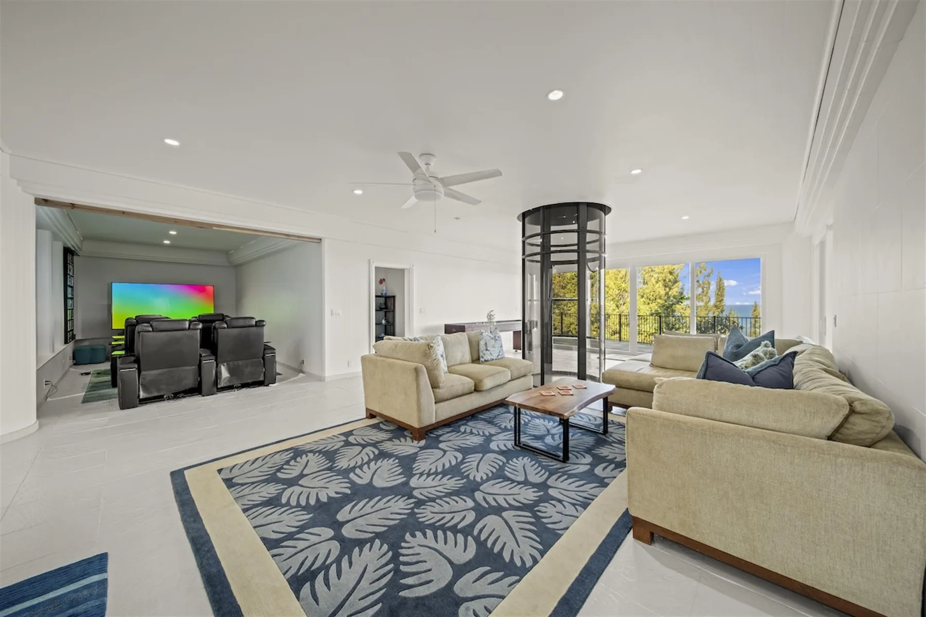 A bright living room with seating, a patterned rug, and a television.