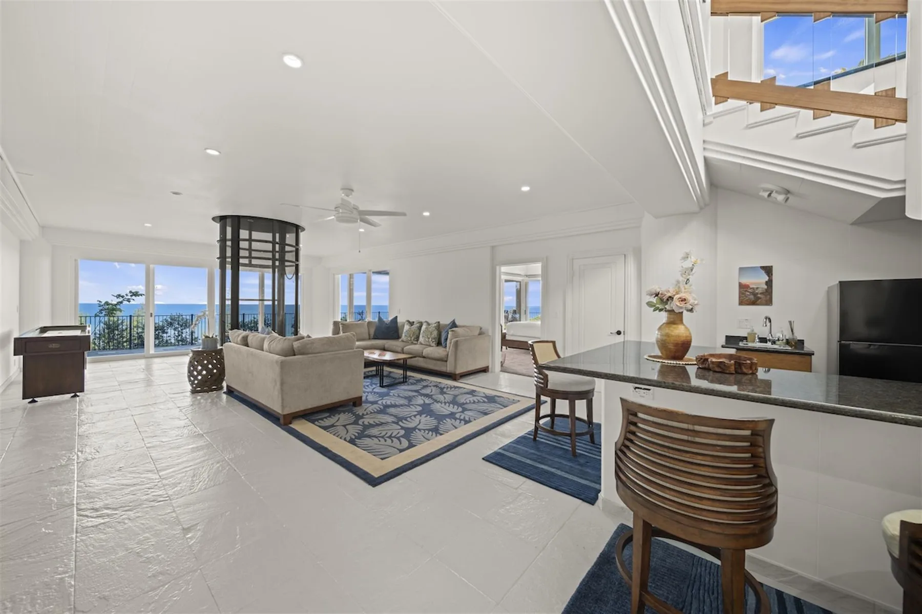 A bright open-plan living and dining area with large windows overlooking the water.