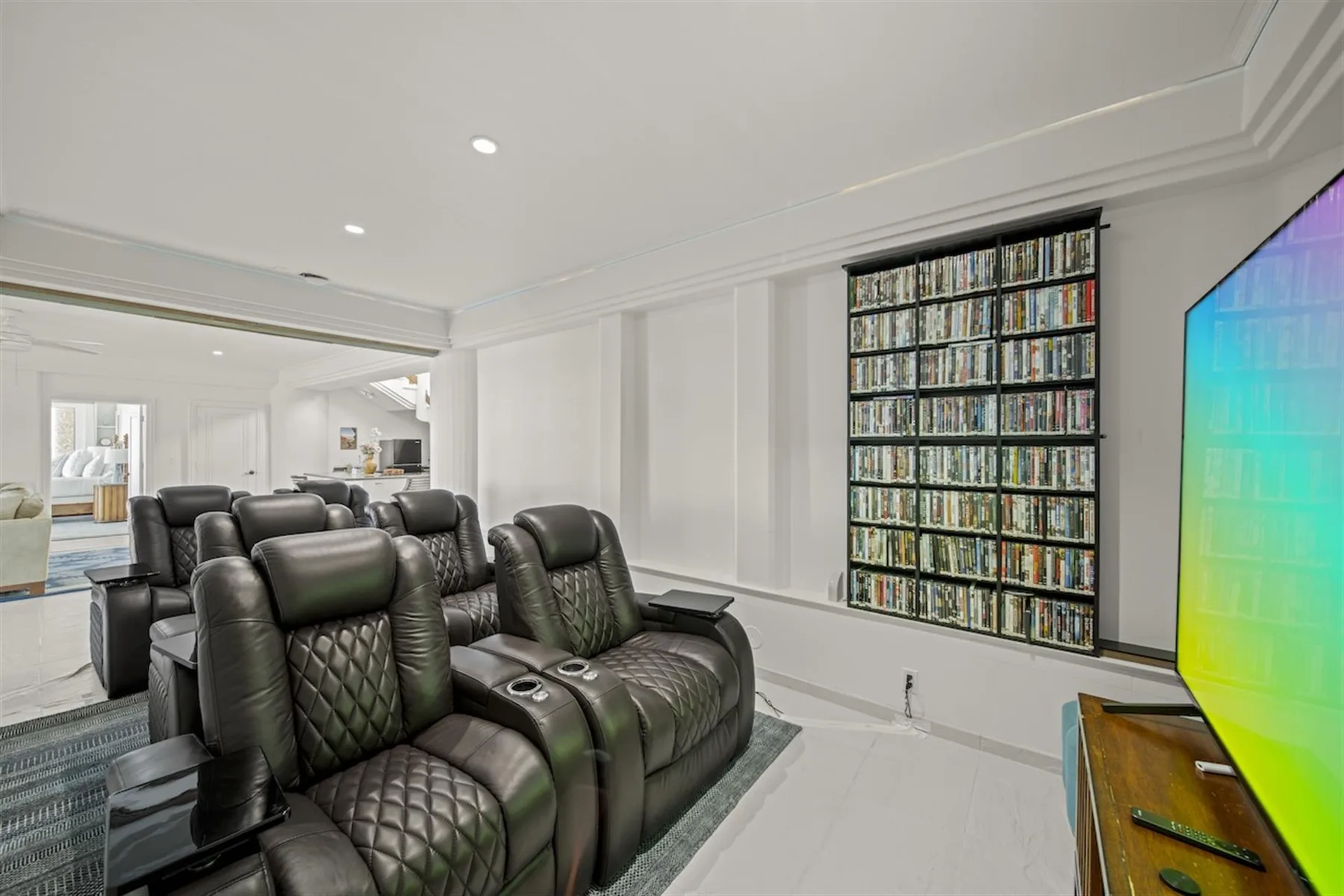 A home theater with rows of reclining seats and a wall of movie cases.