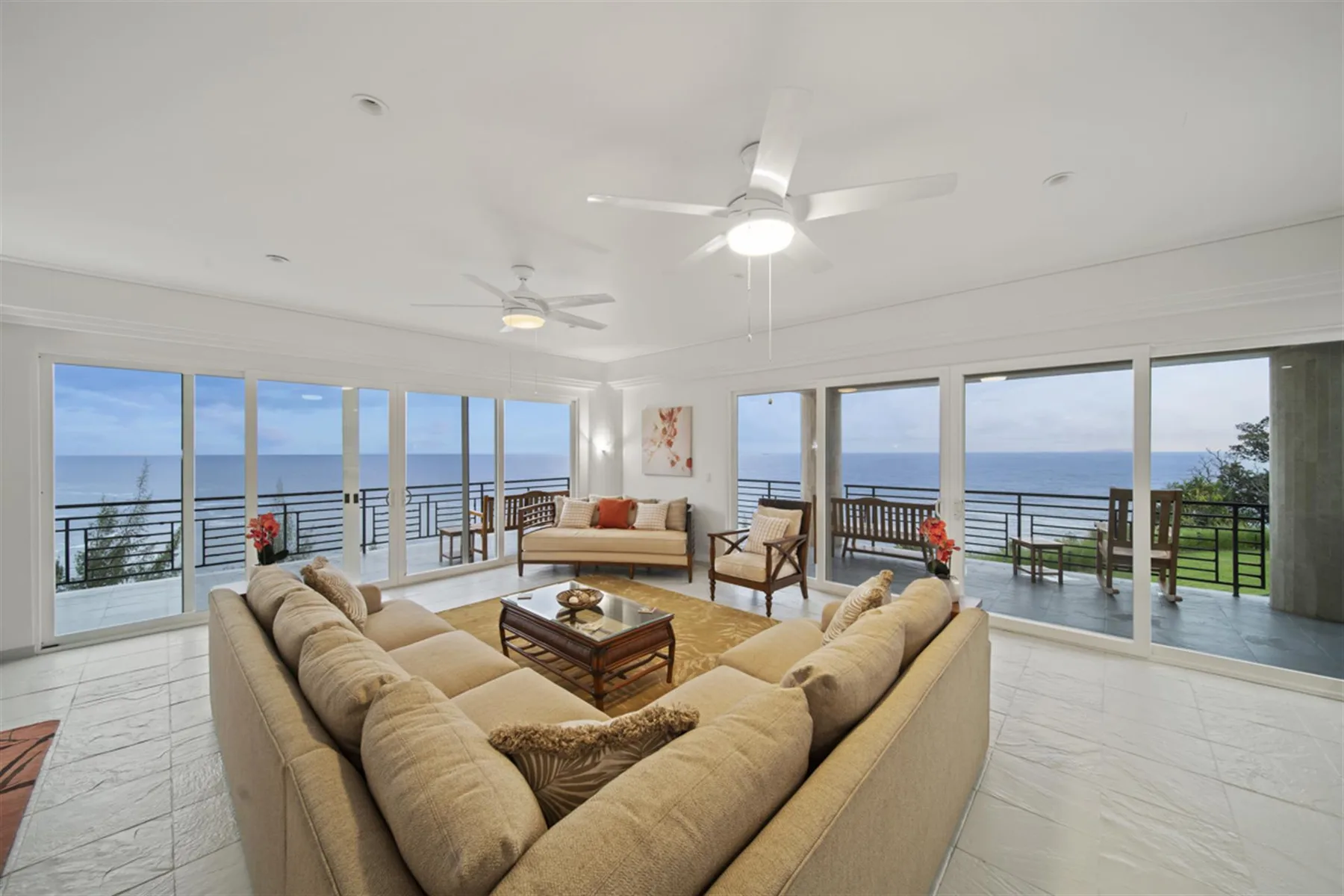 A bright living room opens onto a balcony with ocean views.