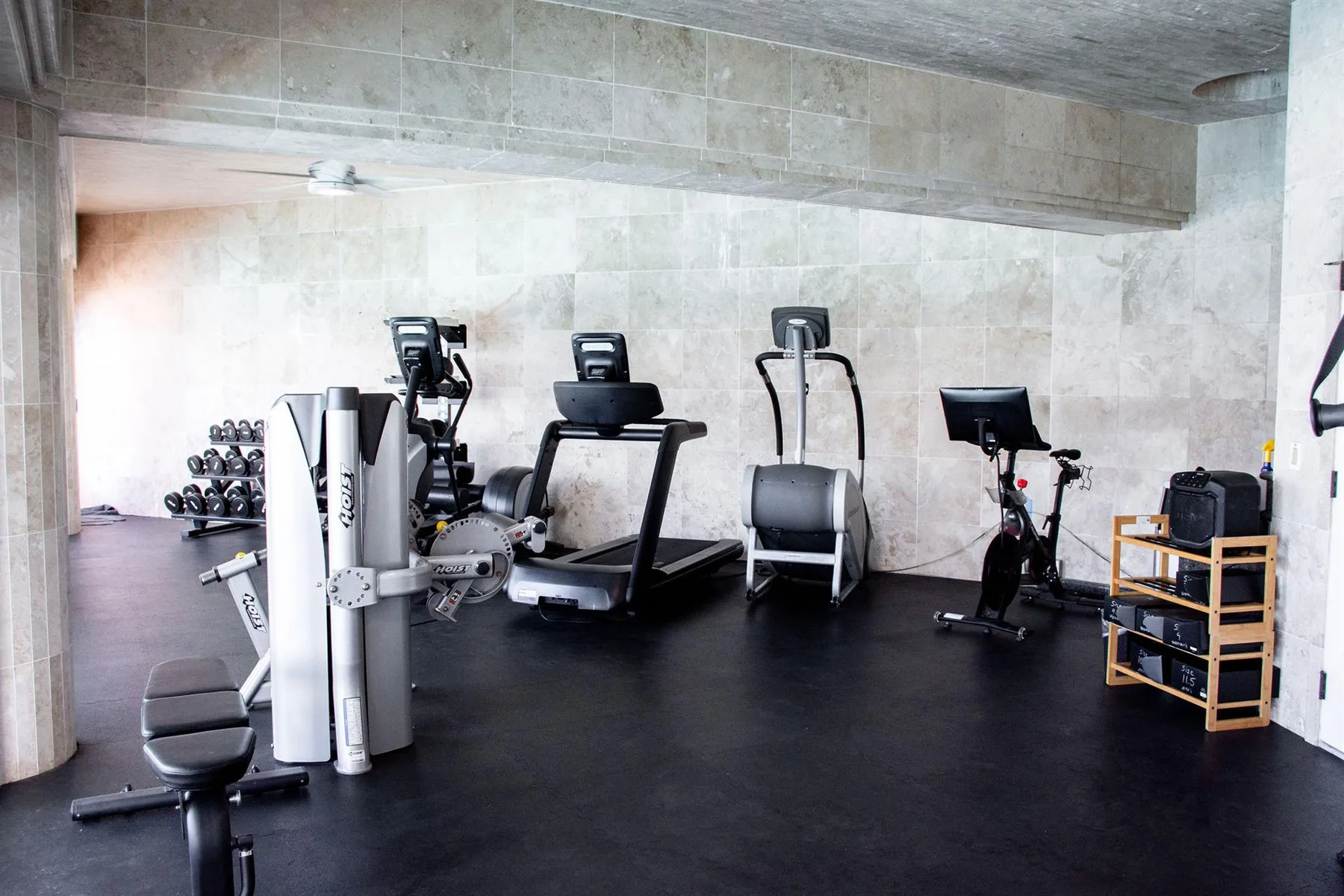 A fitness room with several exercise machines and weights along the wall.