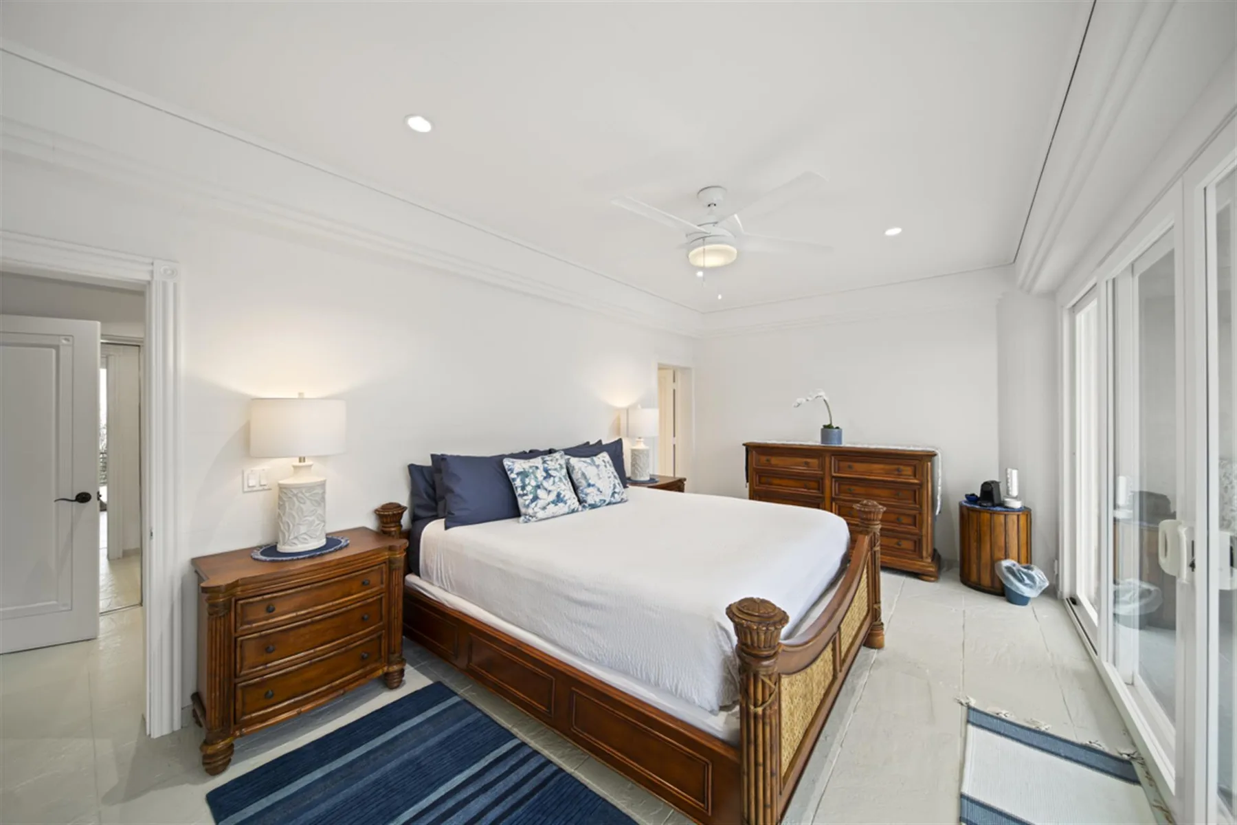 A bright bedroom with a wooden bed and large windows.