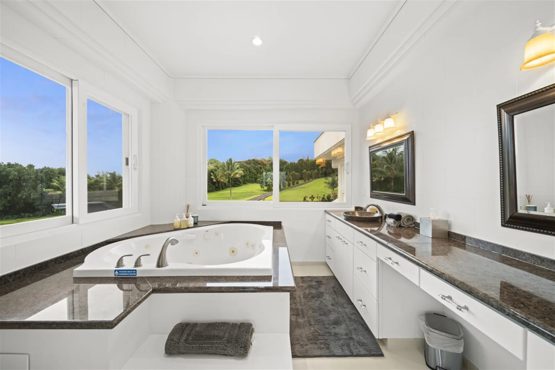 A bright bathroom features a built-in bathtub and a long vanity with a mirror.
