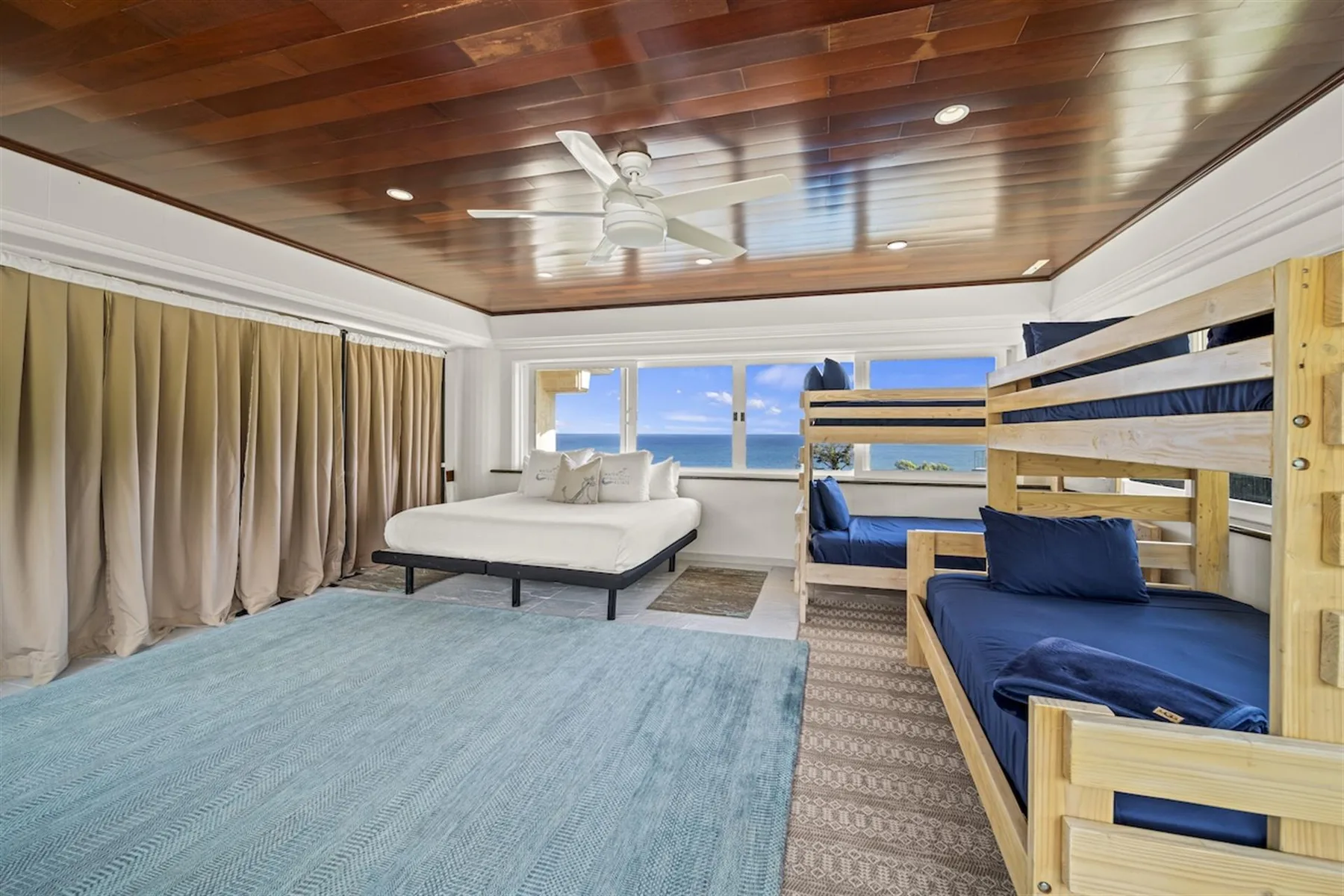 A bedroom with bunk beds and a bed facing windows overlooking the water.
