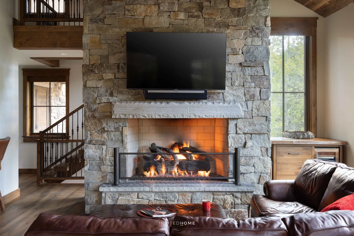 Una sala de estar se centra en una chimenea de piedra con un televisor encima.
