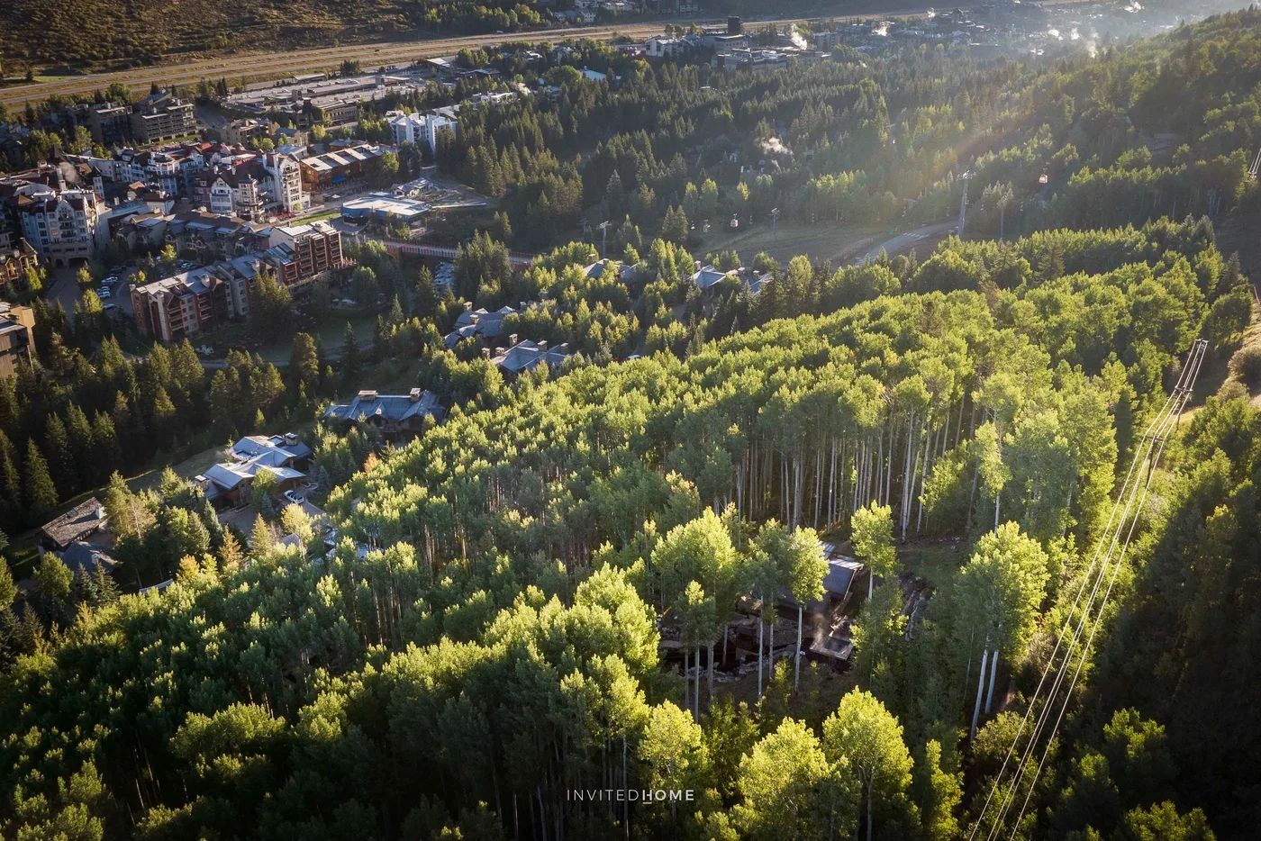 Vista aérea de una ladera boscosa con edificios a lo lejos.
