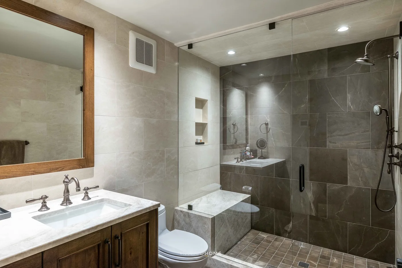 Un baño alicatado con lavabo, inodoro y ducha a ras de suelo.