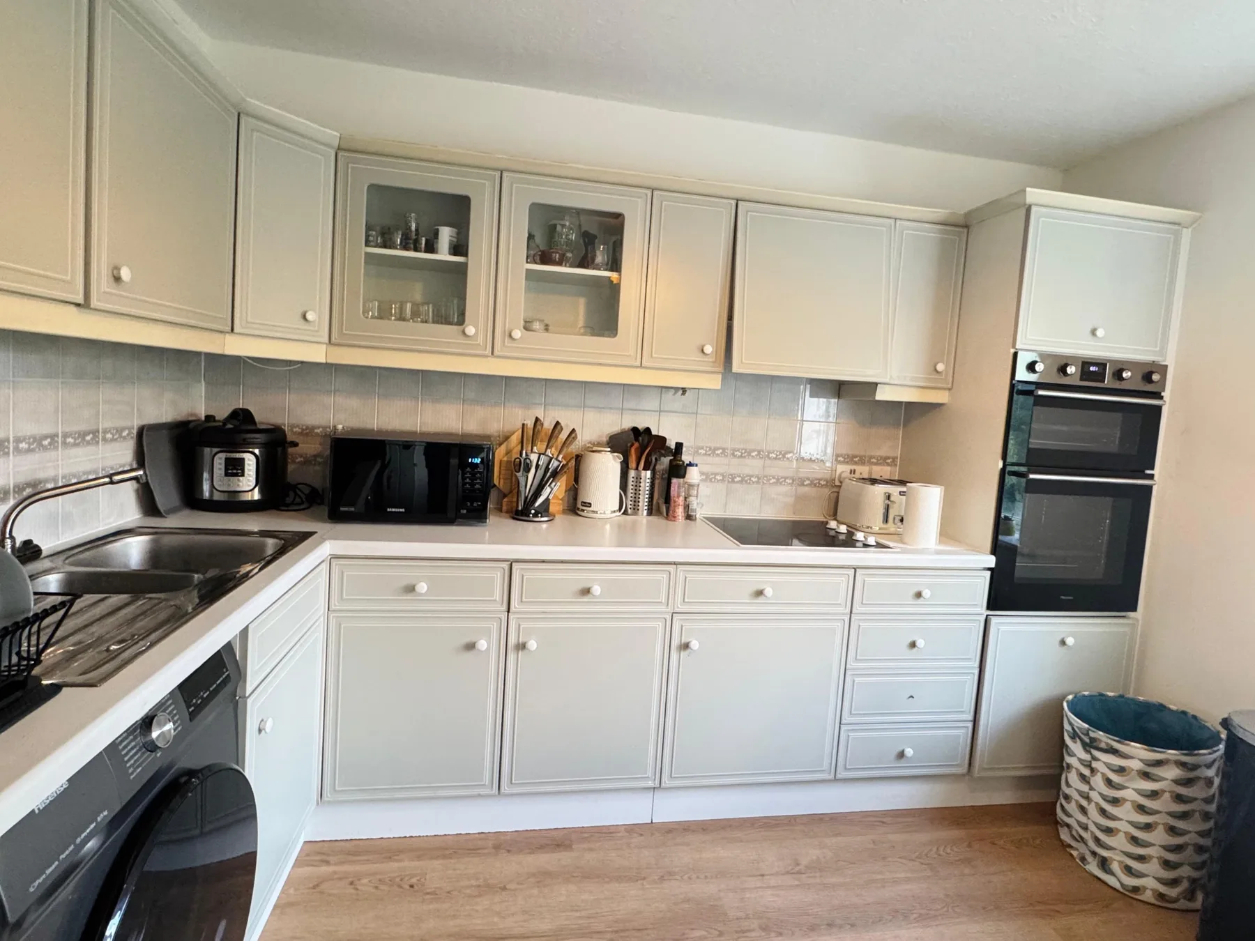 A bright kitchen with white cabinets, countertop appliances, and a built-in oven.
