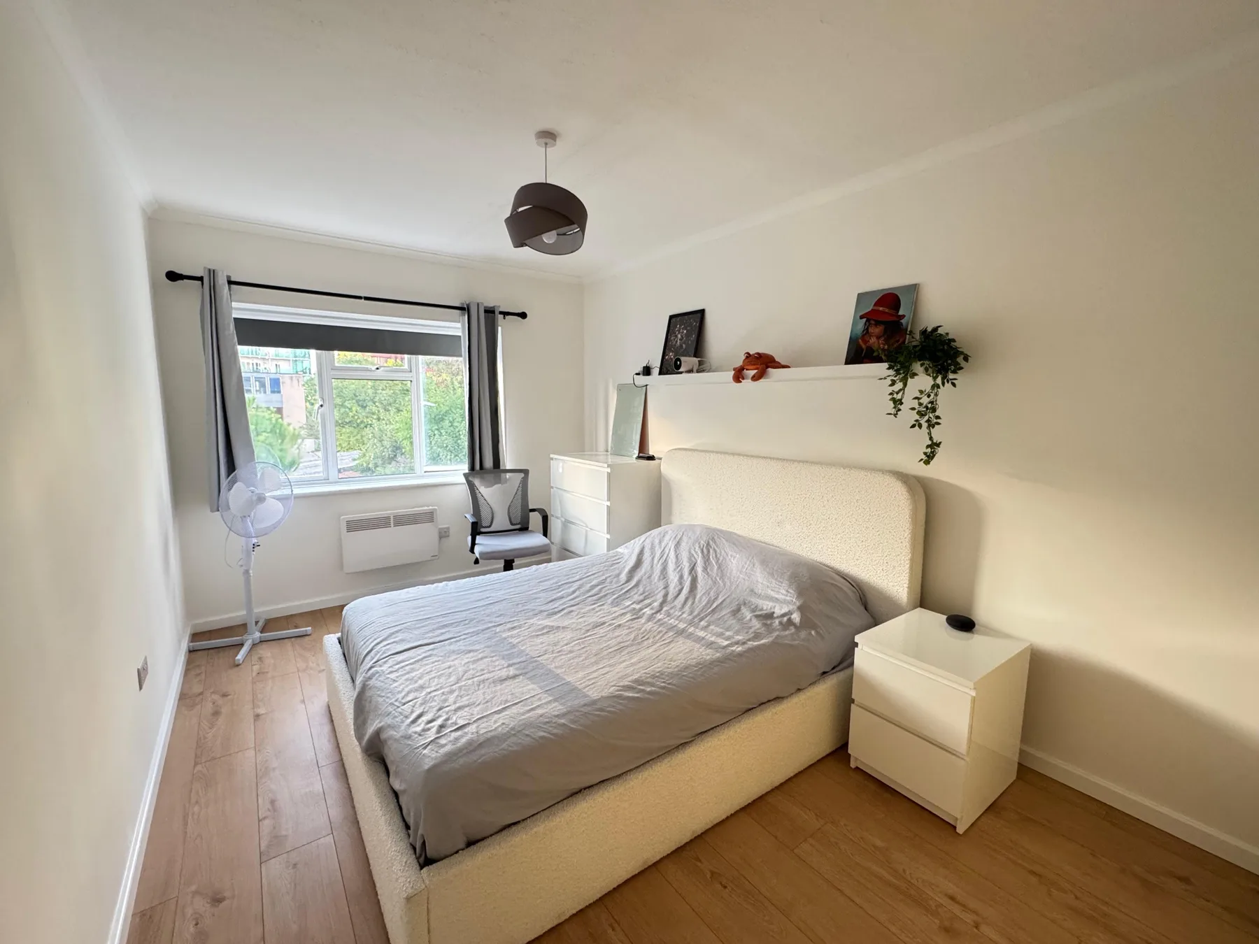 A bedroom with a bed, desk, and a window with curtains.