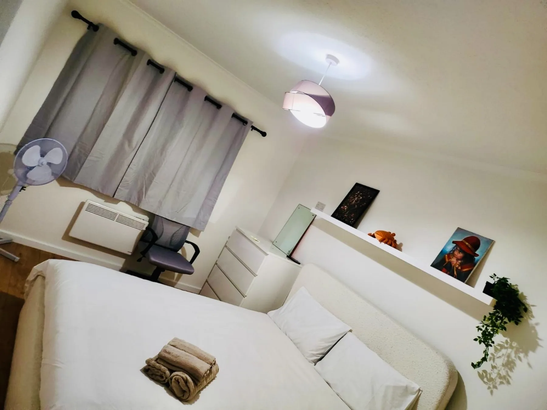 A bedroom with a bed, curtained window, and dresser.