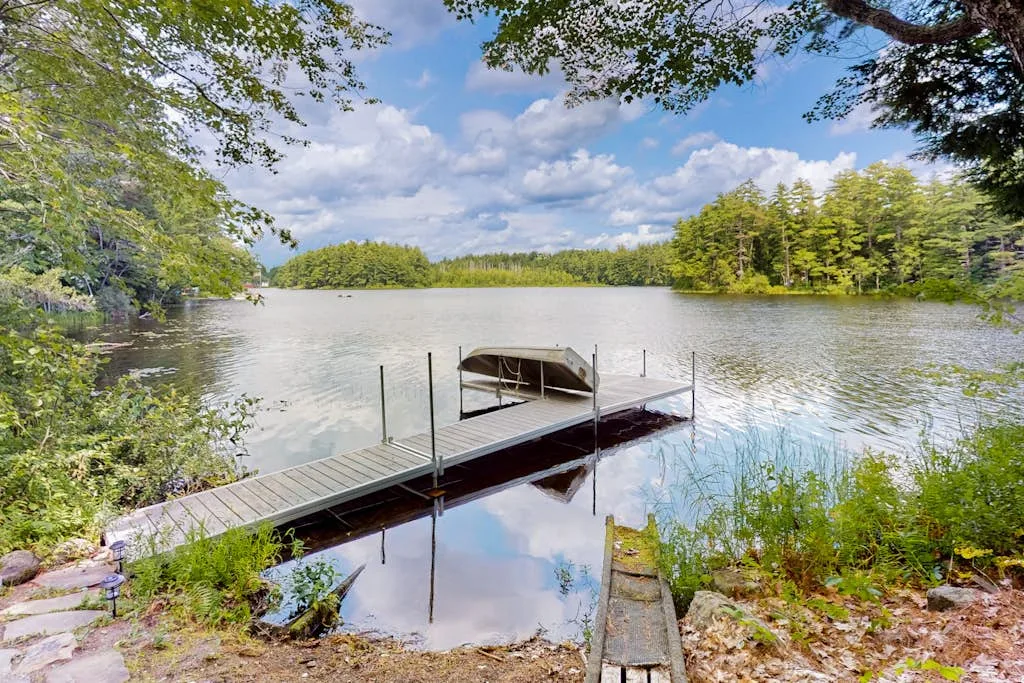 A wooden dock extends across a calm lake surrounded by trees.