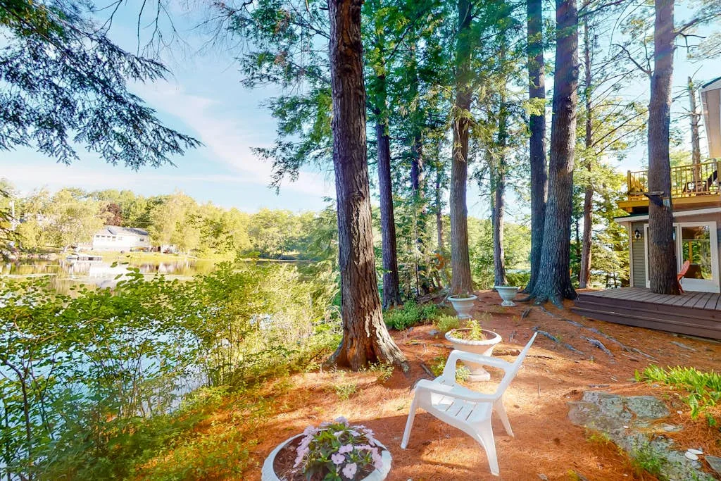 A wooded lakeside deck with a white chair beside the water.