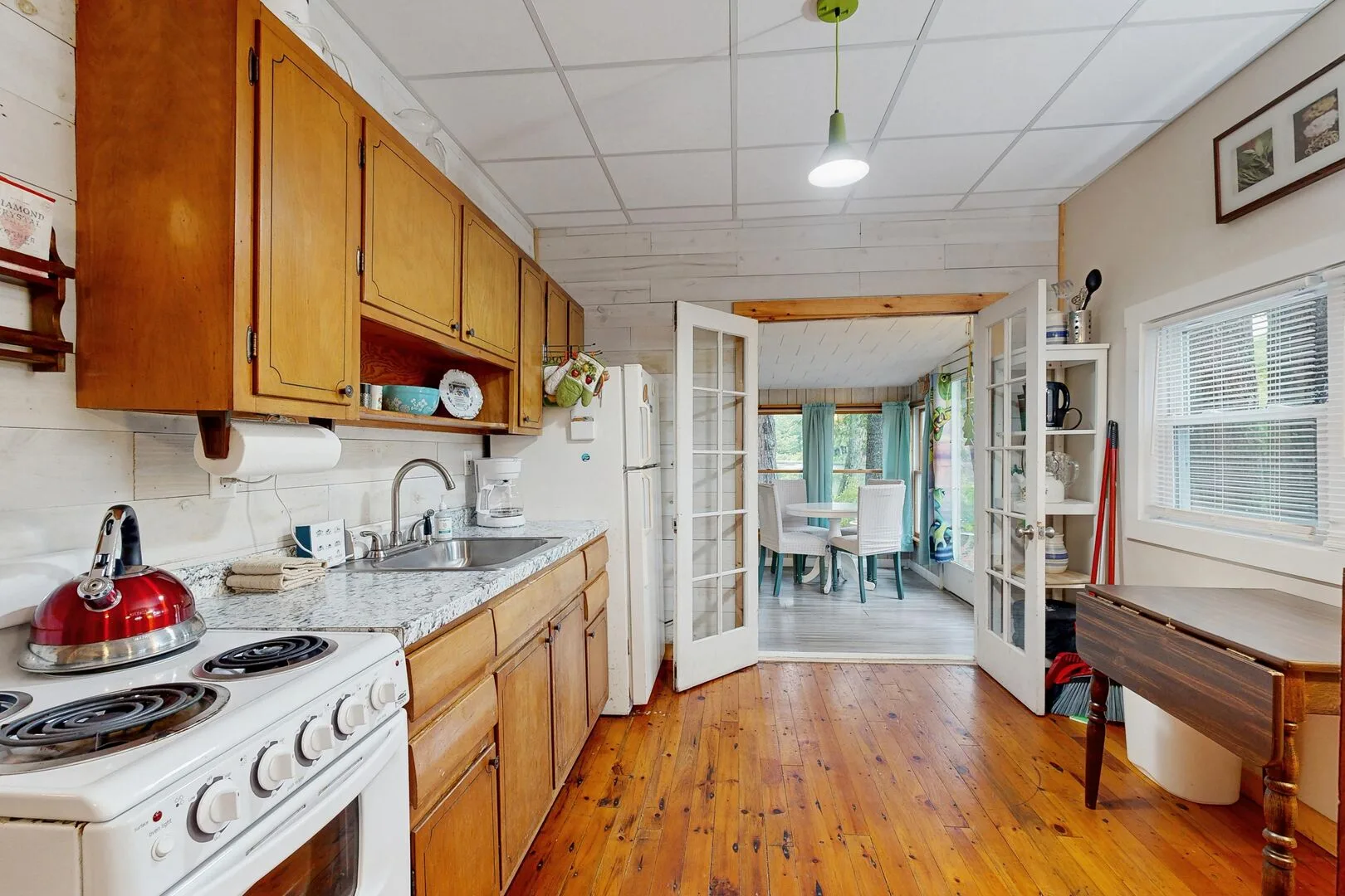 A kitchen with wooden cabinets and a dining table in the adjoining room.