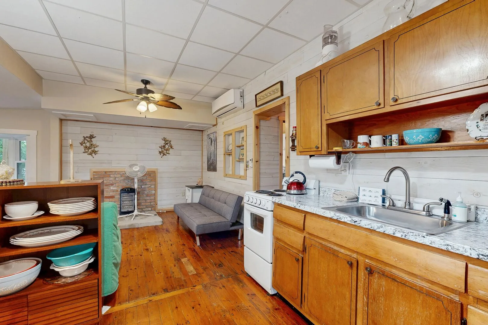 Una cocina compacta y zona de estar con armarios de madera y un sofá pequeño.