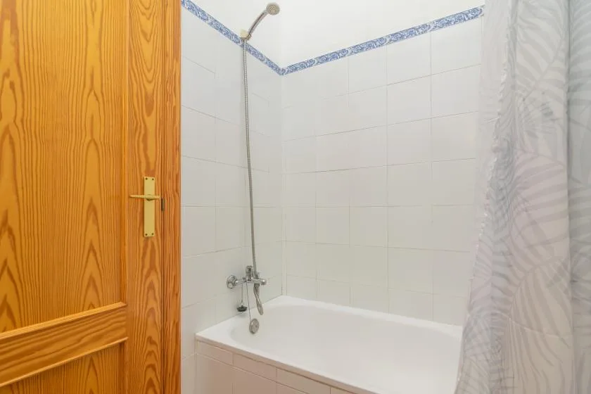 A tiled bathroom with a bathtub, shower fixture, and curtain.