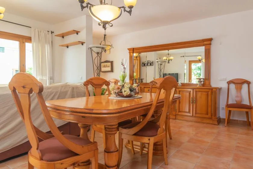 A dining room with a wooden table and chairs beside a large mirrored cabinet.