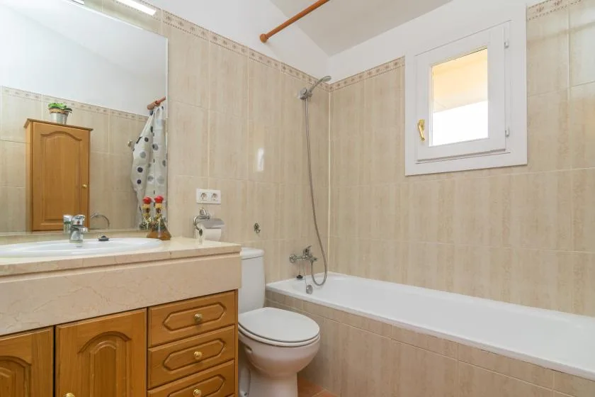 A bathroom with a bathtub, toilet, and wooden vanity.