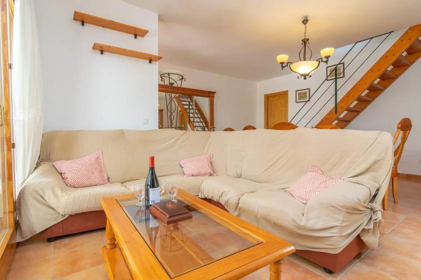 A living room with a large cream-colored sectional sofa and a glass-top coffee table.