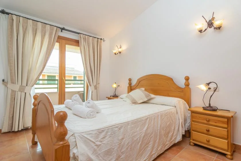 A bedroom with a wooden bed, bedside tables, and a curtained window.