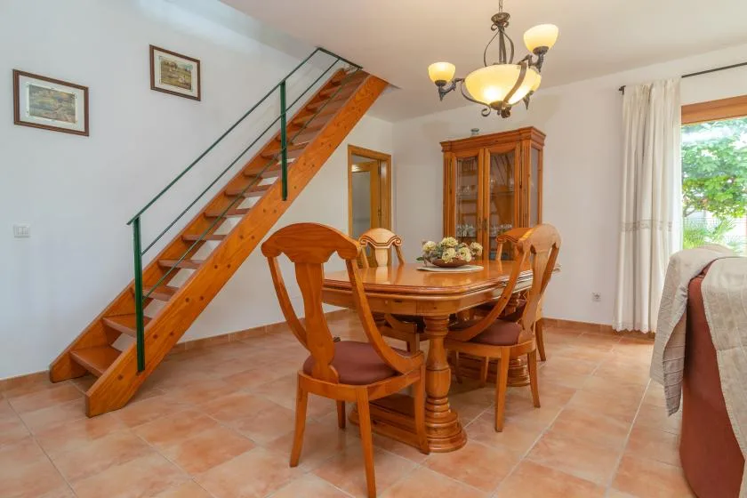 A dining area with a wooden table and chairs beneath a staircase.