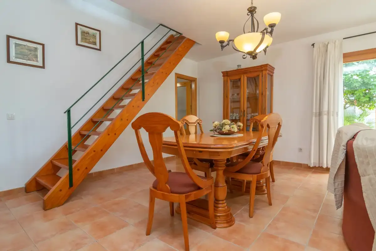 A dining area with a wooden table beneath a staircase.